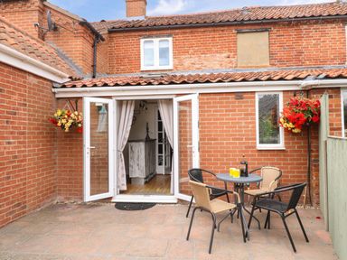 An outdoor area with a table and chairs at Honeysuckle Cottage in Swaffham