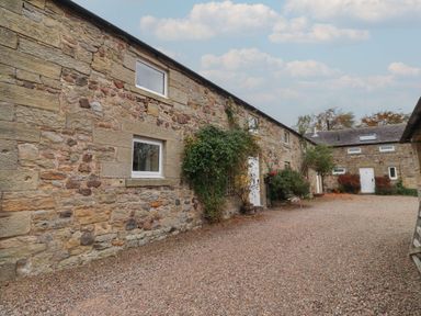 An outdoor view of stone buildings with plants at Honeymug in Branton near Powburn