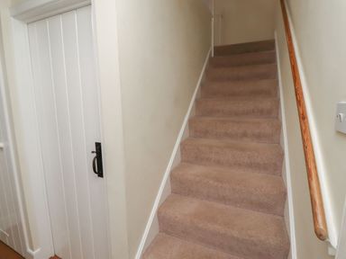 A staircase leading up with a door at the side at Honeymug in Branton near Powburn