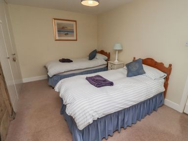 A bedroom with two single beds and a nightstand at Honeymug in Branton near Powburn