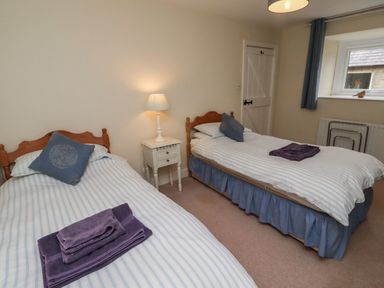 A bedroom with two beds and a bedside table at Honeymug in Branton near Powburn