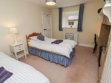 A bedroom with two beds and a bedside table at Honeymug in Branton near Powburn