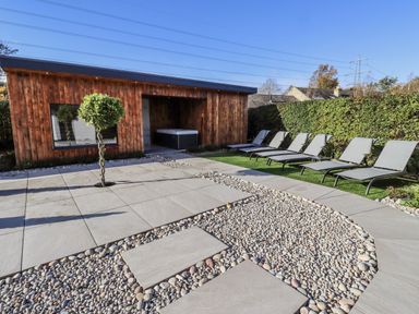 A garden with a wooden building and lounge chairs at Honeymug in Branton near Powburn