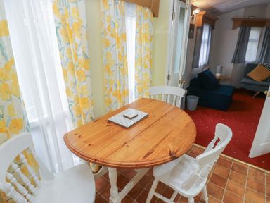 A dining area with a round wooden table and chairs at Static Caravan