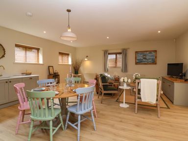 A dining room with colorful chairs and a kitchen area at The Annex Burford