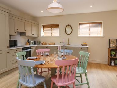 A kitchen with a dining table and colorful chairs at The Annex in Burford