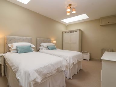 A bedroom with two beds and a wardrobe at The Annex in Burford