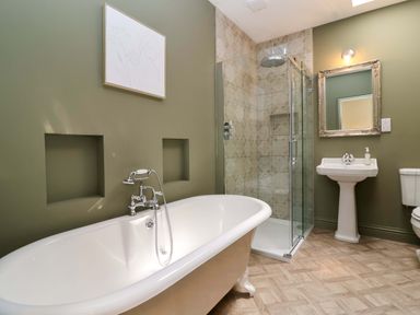 A bathroom with a bathtub, shower, sink, and toilet at The Annex in Burford