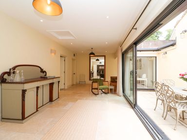 A conservatory with a sideboard and chairs at The Annex in Burford