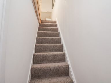 A staircase with carpet and handrail at 1 Castle Terrace in Thirsk