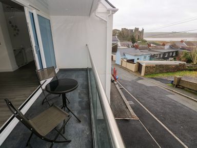 A balcony with a table and chairs overlooking a road at Cottage 1 in Laugharne