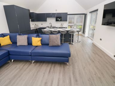 A living room with blue sofa and kitchen area at Cottage 1 in Laugharne