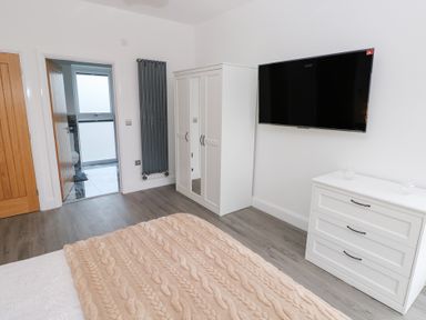 A bedroom with a bed, wardrobe, and TV at Cottage 1 in Laugharne