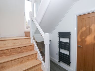 A hallway with stairs and a heated towel rail at Cottage 1 in Laugharne