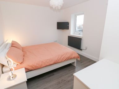 A bedroom with a bed, television and window at Cottage 1 in Laugharne