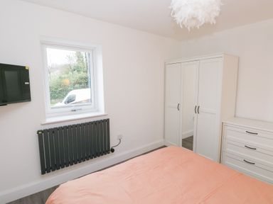 A bedroom with a bed, wardrobe, and television at Cottage 1 in Laugharne