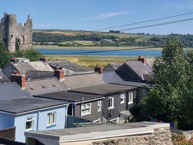 A view of rooftops, a castle and water at Milkwood Villa in Laugharne