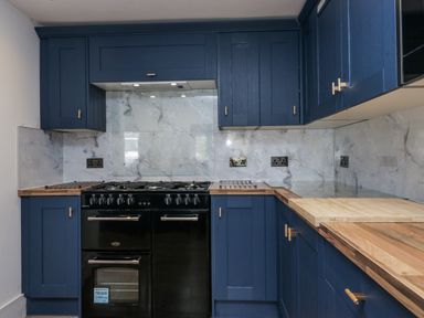 A kitchen with blue cabinets and a black gas stove at Aspen Boutique