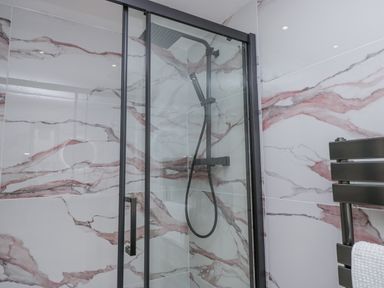 A bathroom with a glass shower and marble wall tiles at Aspen Boutique