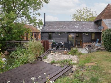 An outdoor area with a wooden deck and a table and chairs at WEST LODGE in Ashford