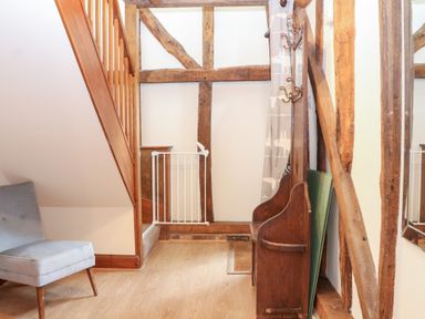 A hallway with a staircase and a chair at WEST LODGE in Ashford