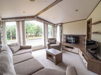 A living room with a sofa and a television at Beach Retreat E19 Dyffryn Seaside Estate Dyffryn Ardudwy