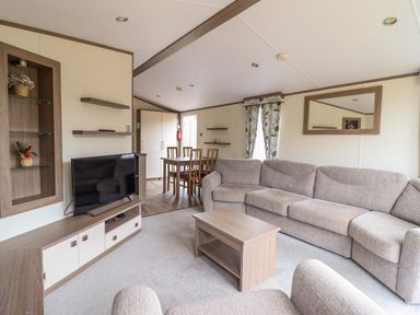 A living room with a sofa and dining table at Beach Retreat E19 Dyffryn Seaside Estate Dyffryn Ardudwy