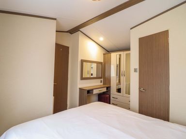 A bedroom with a bed and wardrobe at Beach Retreat E19 Dyffryn Seaside Estate Dyffryn Ardudwy