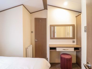 A bedroom with a bed, desk, mirror, and door at Beach Retreat E19 Dyffryn Seaside Estate Dyffryn Ardudwy