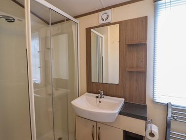 A bathroom with a shower, sink, and mirror at Beach Retreat E19 Dyffryn Seaside Estate Dyffryn Ardudwy