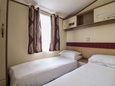 A bedroom with two beds and curtains at Beach Retreat E19 Dyffryn Seaside Estate Dyffryn Ardudwy