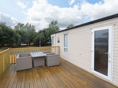 A deck with outdoor furniture at Beach Retreat E19 Dyffryn Seaside Estate in Dyffryn Ardudwy