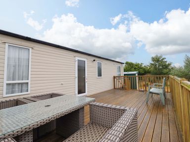 An outdoor space with a wooden deck, table, and chairs at Beach Retreat E19 Dyffryn Seaside Estate Dyffryn Ardudwy
