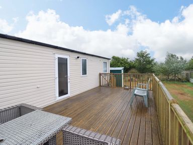 An outdoor deck with a table and chairs at Beach Retreat E19 Dyffryn Seaside Estate Dyffryn Ardudwy