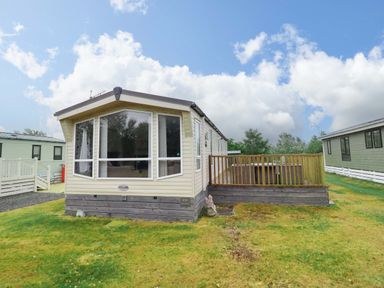 A caravan with a wooden deck at Beach Retreat E19 Dyffryn Seaside Estate Dyffryn Ardudwy