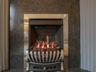 A fireplace with glowing coals at Gavin and Stacey House in Barry
