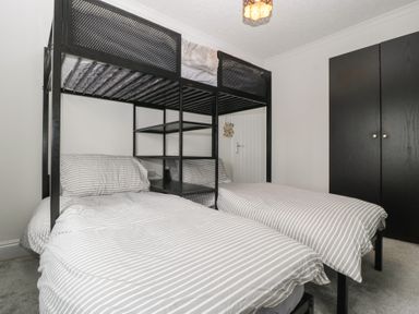 A bedroom with a bunk bed and a wardrobe at Gavin and Stacey House in Barry
