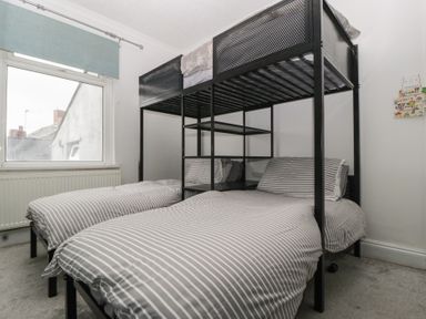 A bedroom with a bunk bed and a single bed at Gavin and Stacey House in Barry