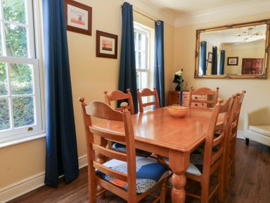 A dining room with a wooden table and chairs at Ty Caredig Swansea