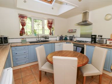 A kitchen with a table and chairs along with appliances at Ty Caredig in Swansea