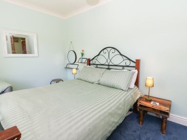 A bedroom with a bed and a mirror at Ty Caredig in Swansea