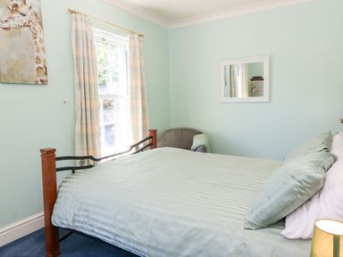 A bedroom with a bed and window at Ty Caredig in Swansea