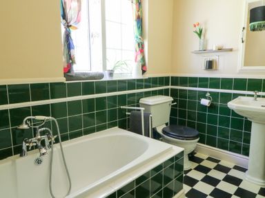 A bathroom with a bathtub, toilet, and sink at Ty Caredig in Swansea