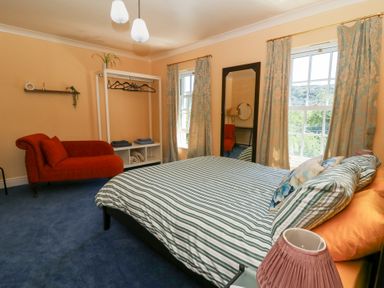 A bedroom with a bed, sofa, and mirror at Ty Caredig in Swansea