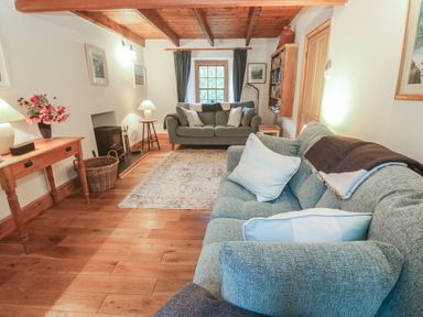 A living room with a sofa and table at 1 Rowes Cottages in Penzance