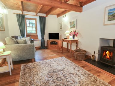 A living room with a sofa, television, and a fireplace at 1 Rowes Cottages Penzance