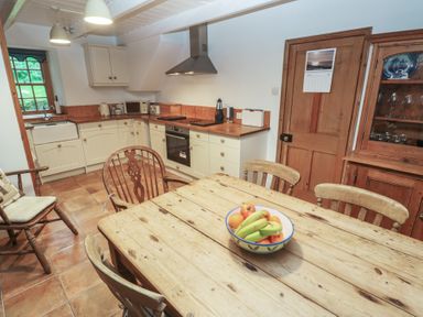 A kitchen with a wooden table and chairs at 1 Rowes Cottages in Penzance