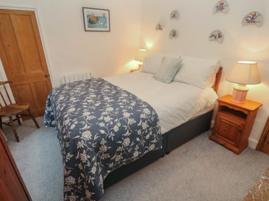 A bedroom with a bed and a chair at 1 Rowes Cottages in Penzance