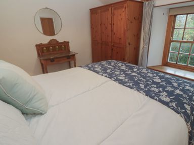 A bedroom with a bed and wooden furniture at 1 Rowes Cottages in Penzance