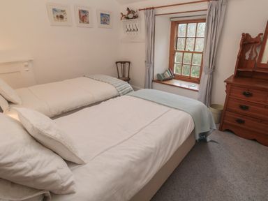 A bedroom with two beds and a window at 1 Rowes Cottages in Penzance